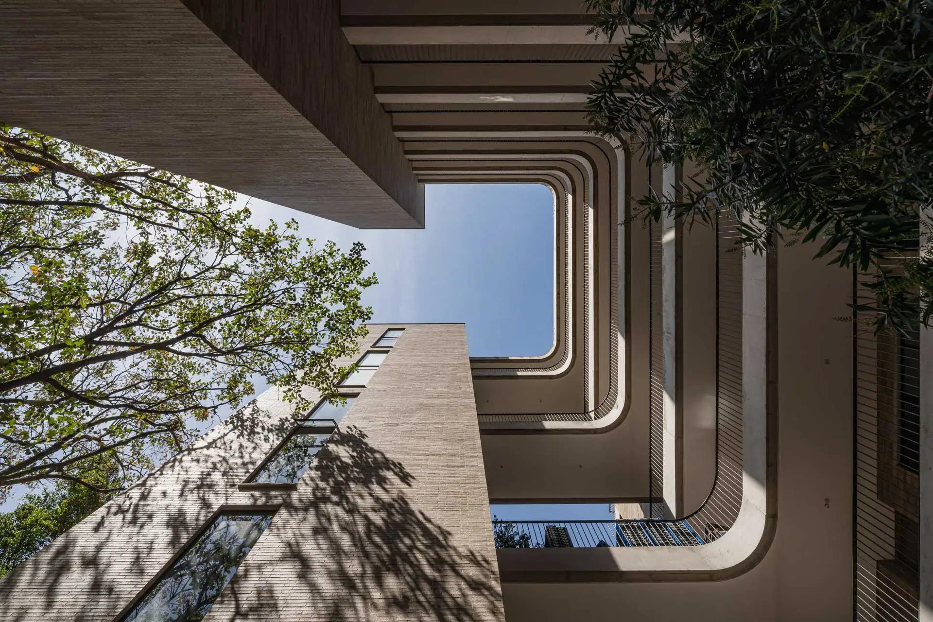 Detalle de las escaleras voladas de concreto y pasamanos metálicos negros.